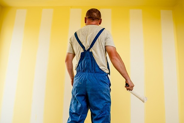 A man in overalls holding a paint roller