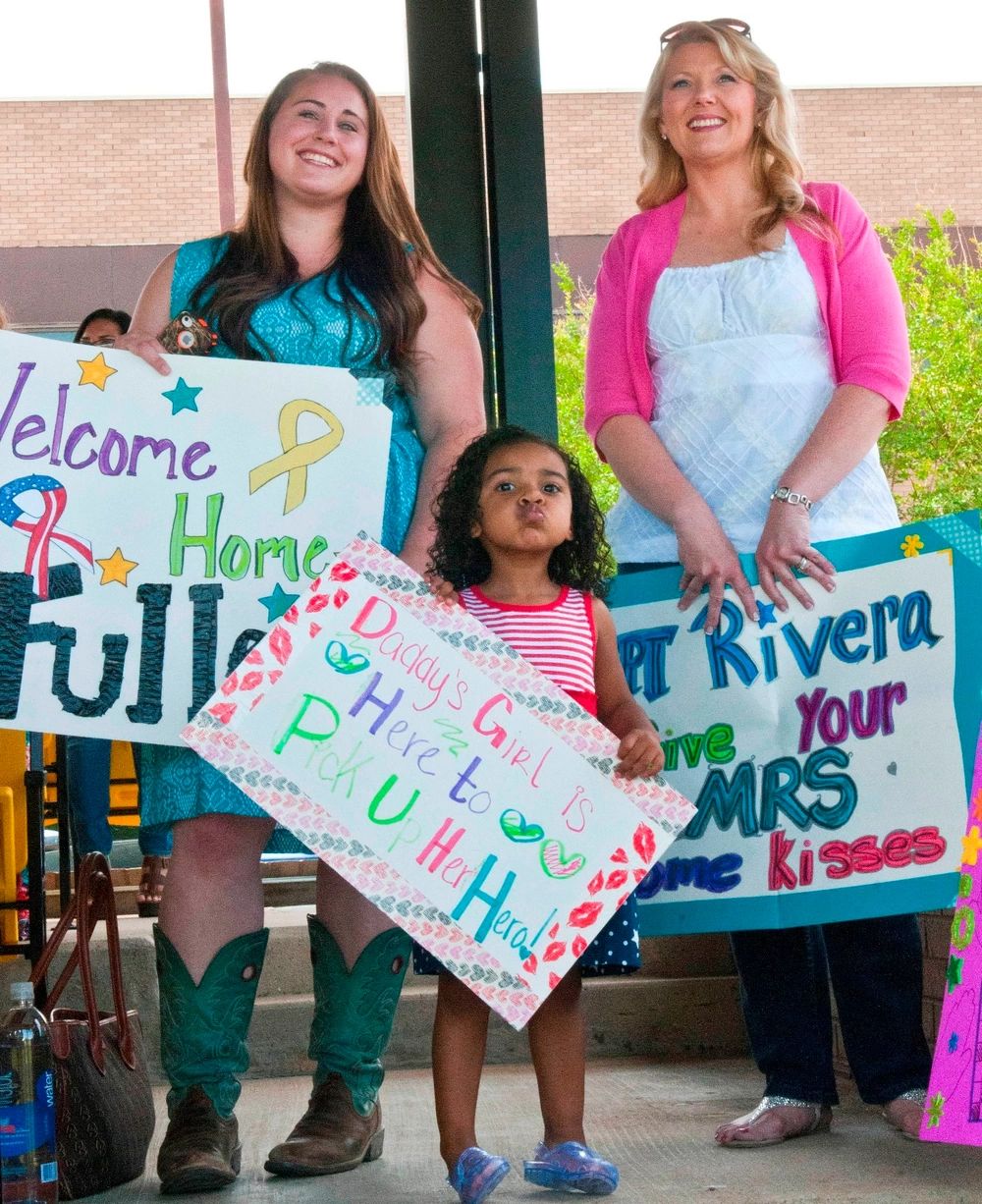 Two women with Cute kid is standing with a poster