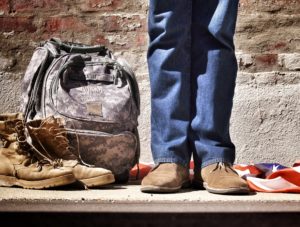 A person standing on a rocky surface with backpack -Loans for Veterans